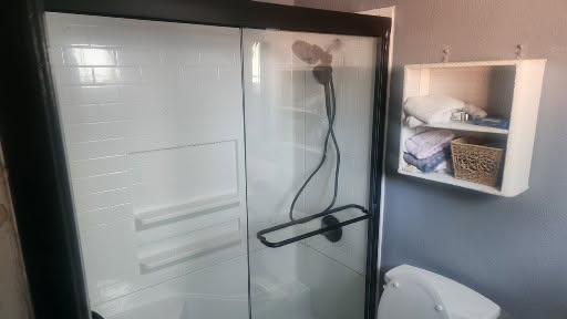 Shower with white tile surround and black-framed sliding glass doors